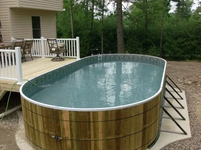 Овальный каркасный бассейн смонтирован у деревянной веранды.